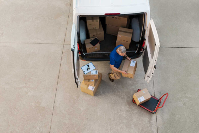 Delivery,Man,Holding,Cardboard,Box,And,Unloading,Parcel,For,Delivery.