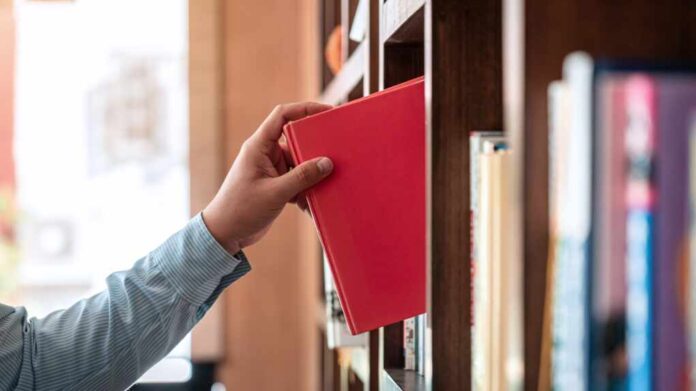 Close,Up,Of,Asian,Man,Checking,Interesting,Book,From,Bookcase